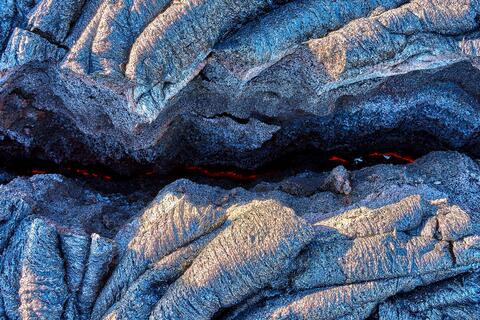 the earth is glowing red hot through a crack in the dried lava on the big island of Hawaii.  Lava Photography by Andrew Shoemaker