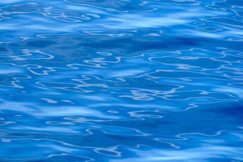 A blue water abstract photography image featuring interesting patterns of the reflections on the surface of the water off the coast of Maui, Hawaii. 