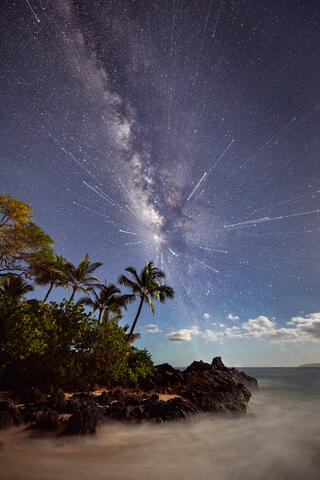 a mix of two long exposure photographs and one with a zoom lens gives a hyperspace effect to this milky way night scene at Secret Beach in Makena Maui