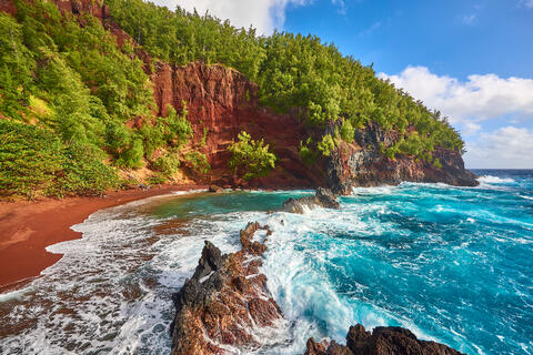 an amazing red sand beach with incoming aqua blue waves located in Hana, Hawaii on the island of Maui 