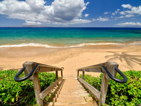 a photograph looking down a staircase at Ulua Beach in Wailea on the island of Maui into the beautiful Pacific Ocean.  Photography by Andrew Shoemaker