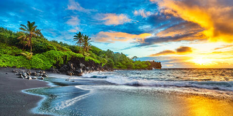 a vibrant sunrise at the famous black sand beach at Waianapanapa State Park near Hana on the island of Maui, Hawaii.