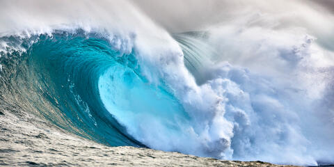 an emerald colored panoramic photograph of the biggest wave in Hawaii Jaws on the island of Maui.  Photographed by Andrew Shoemaker 