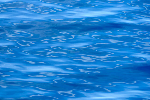 A blue water abstract photography image featuring interesting patterns of the reflections on the surface of the water off the coast of Maui, Hawaii. 