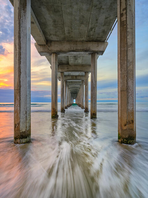 Entranced is a fine art photograph at sunset looking down Scripps Pier is La Jolla, California near San Diego featuring beautiful color and water motion.  