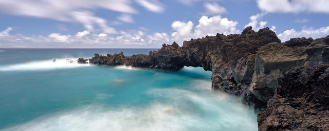 eternal echoes is a long exposure photograph from waianapanapa state park featuring a black lava rock arch extending out to the turquoise waters