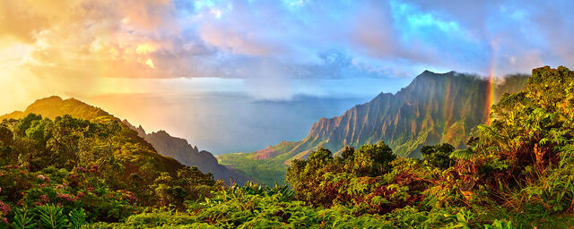 panoramic view of the Kalalau Valley on the island of Kauai with a rainbow and a dramatic sunset along the Na Pali Coast 