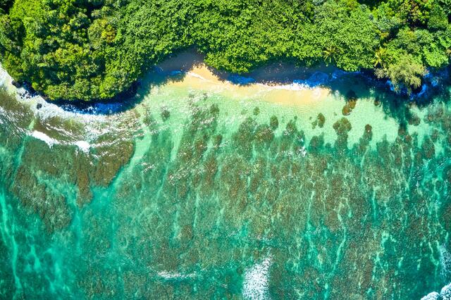 an aerial photograph showing the reefs and the beautiful turquoise waters of Hideaways Beach on the north shore of the island of Kauai. 