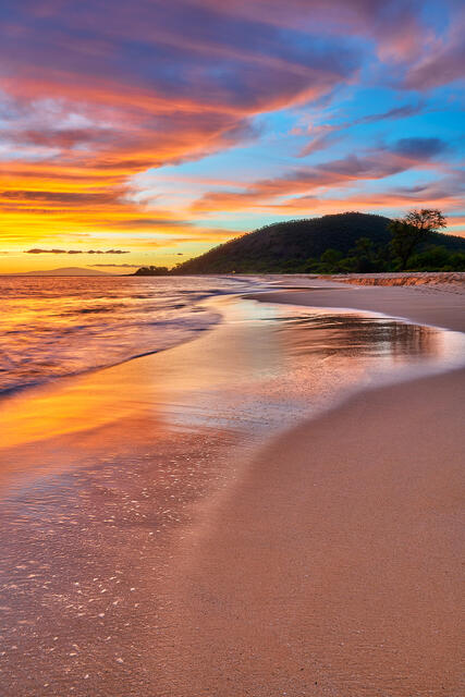 vertical photograph of sunset at Big Beach at Makena State Park in Maui, Hawaii.   The sunset clouds seems to mirror the incoming waves on the beach