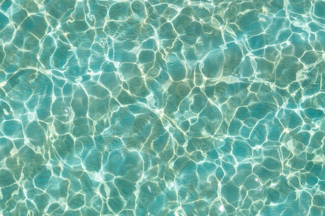 Abstract aerial-style photograph of turquoise ocean water in Maui, featuring soft ripples and shimmering sunlight patterns creating a calming, meditative textur