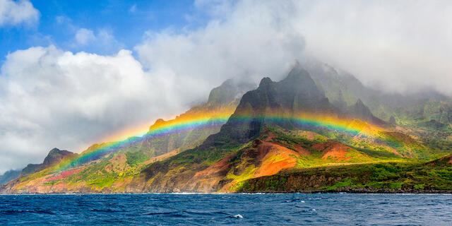 A panoramic view of a vibrant rainbow along the na pali coast on the Hawaiian island of Kauai