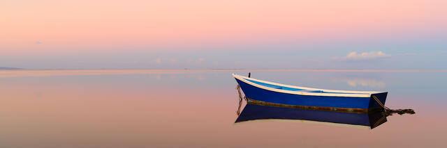 a lone boat reflects in the calm waters of the pacific ocean off the coast of the Hawaiian island of Molokai.  Fine art limited edition Hawaii photography