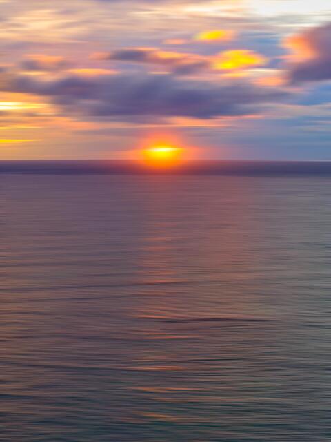 Abstract fine art photograph of a Maui sunset over the Pacific Ocean, featuring soft motion blur, warm light, and a minimal horizon.