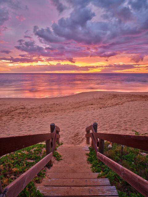 stairway down to a beautiful beach on the Hawaiian island of Maui at sunset featuring pink, purple, and orange colors.  Photographed by Andrew Shoemaker