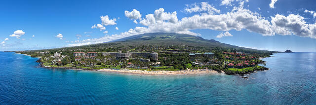 Aerial panorama of Wailea Beach on Maui, Hawaii, showing turquoise water, golden sand, luxury oceanfront resorts, and Haleakalā rising in the background.