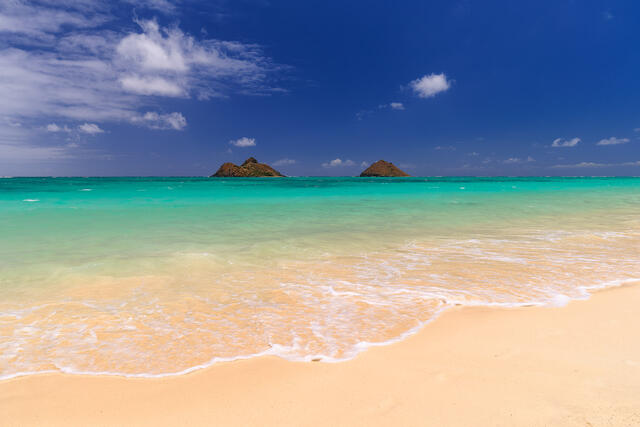 daytime photograph of the beautiful Lanikai Beach on the Hawaiian island of Oahu with white sand, amazing turquoise water color and the Mokulua islands 