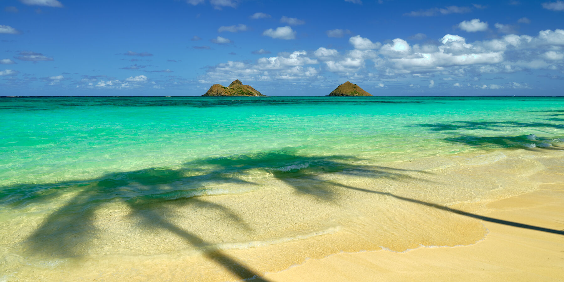 Serendipity Panorama Serendipity is a fine art photograph from Andrew Shoemaker at Lanikai Beach on the Hawaiian island of Oahu featuring azure waters and two islands on the horizon