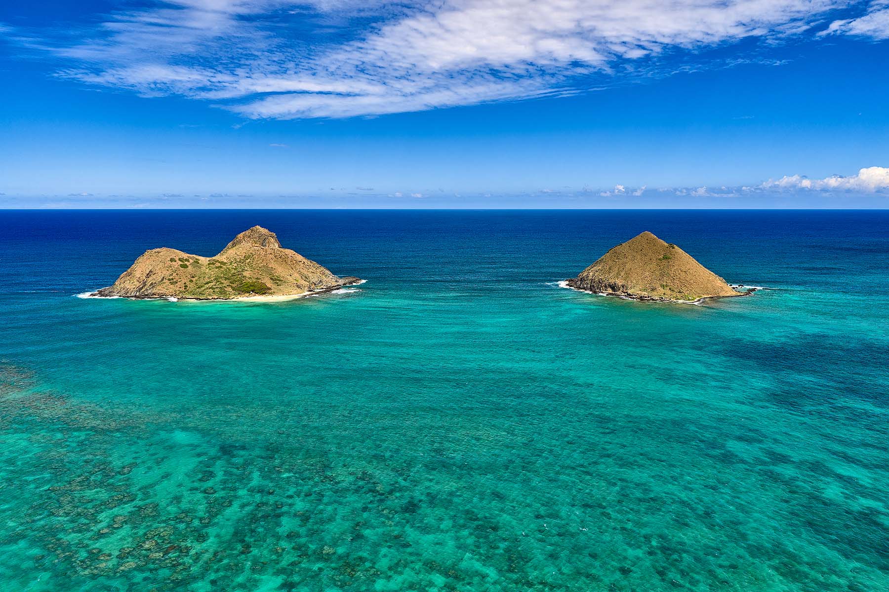 Twin Jewels Aerial photograph of the Mokulua Islands surrounded by turquoise ocean and coral reefs off Lanikai Beach on Oahu, Hawaii.