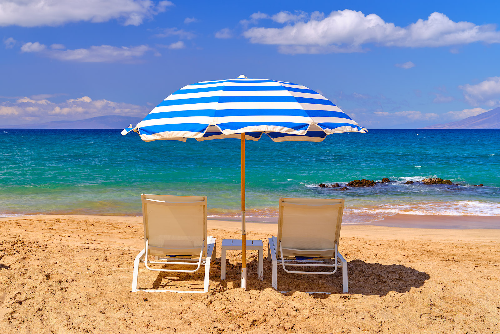 a Hawaii beach scene in Makena Maui at Maluaka Beach featuring a beach umbrella and 2 chairs.  Hawaii fine art nature photography by Andrew Shoemaker