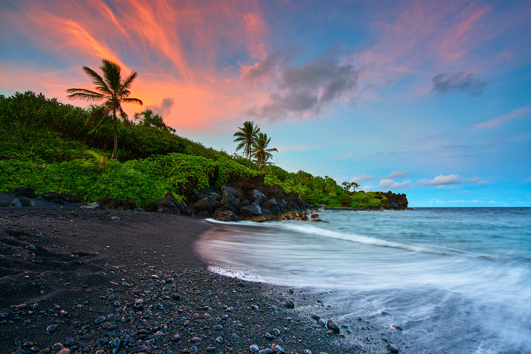 Crown Jewel A glorious sunset at the black sand beach of Waianapanapa State Park in Hana, Hawaii. Incoming wave crashes on to the beach