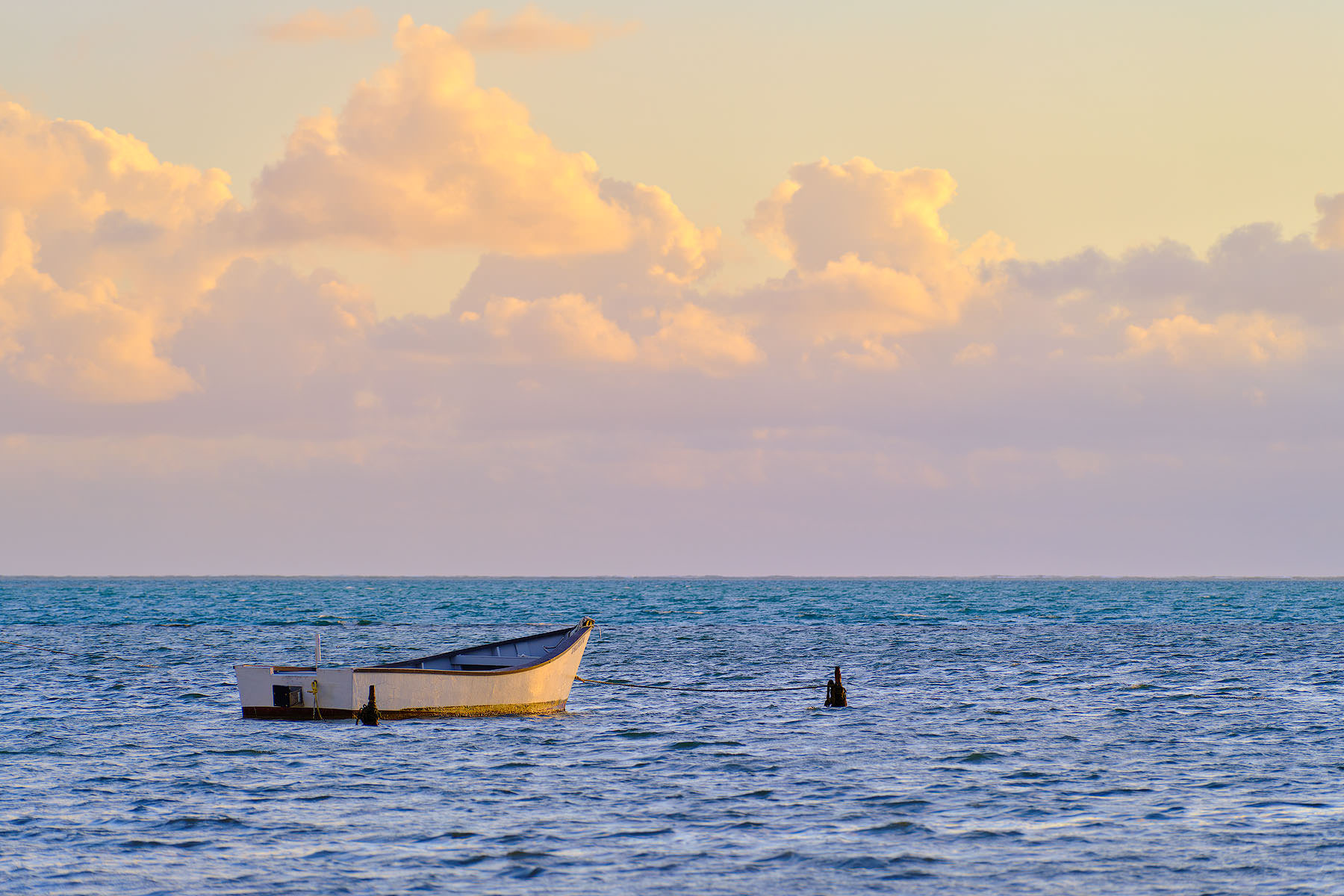 A lone fishing boat reflecting the beautiful sunrise on the calm waters of Kaneohe Bay on the Hawaiian island of Oahu.  Hawaii fine art photography