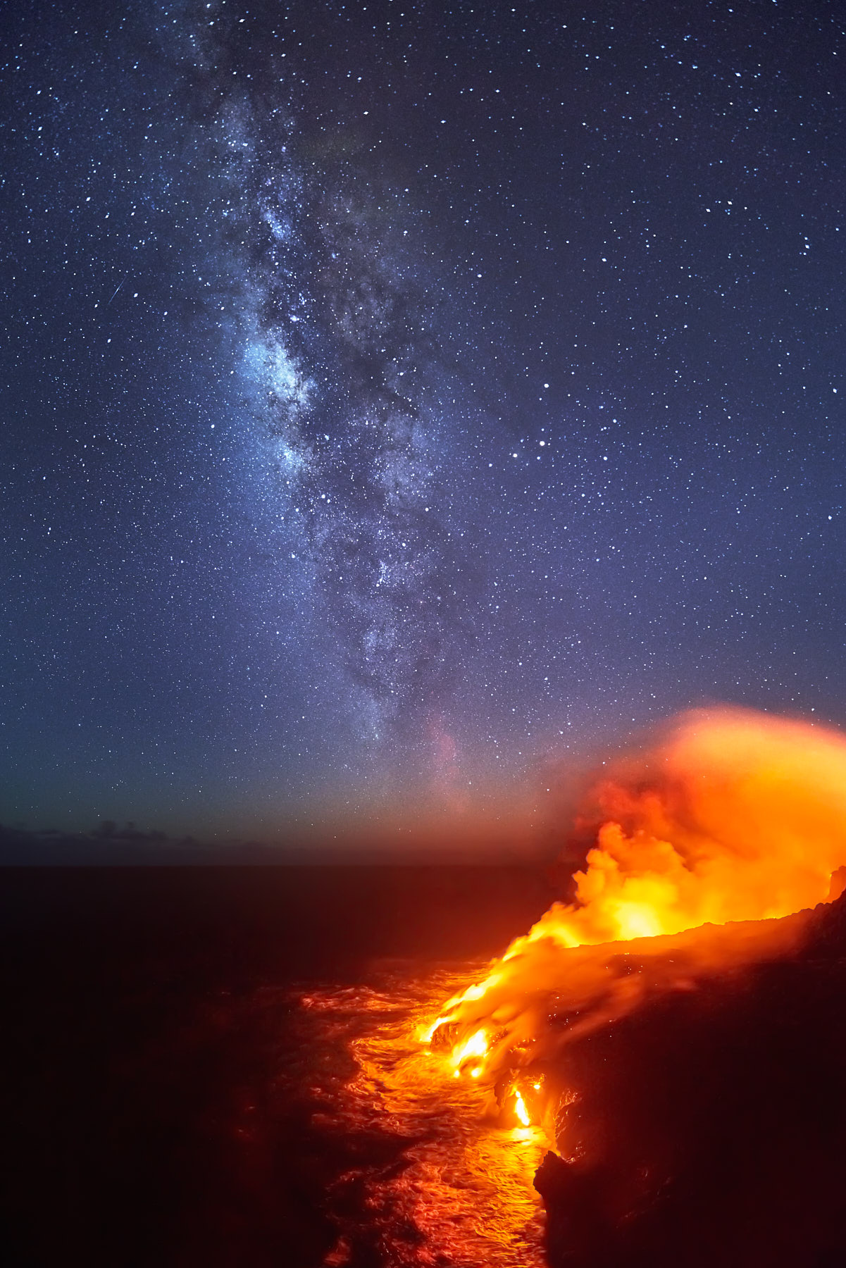 the volcanic lava meets the pacific ocean at Hawaii Volcanoes National Park with the stars and Milky Way galaxy rising over the pacific.