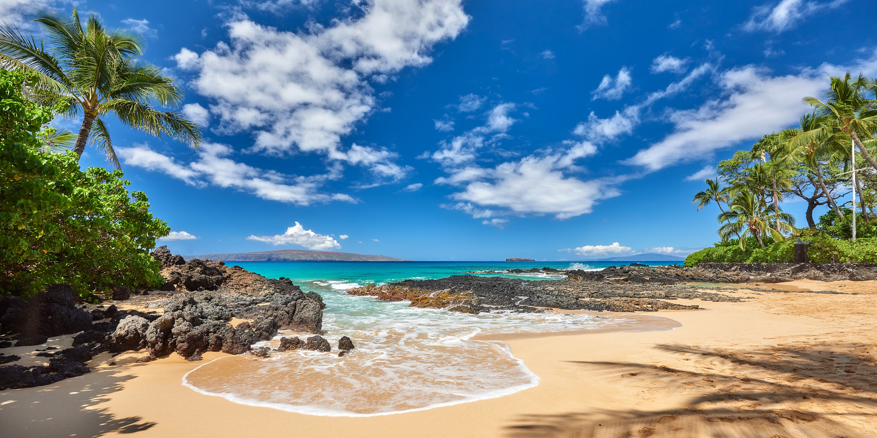 panorama of a perfect morning at Secret Beach (also known as Makena Cove) on the island of Maui, Hawaii.  Blue sky, turquoise water and palm trees