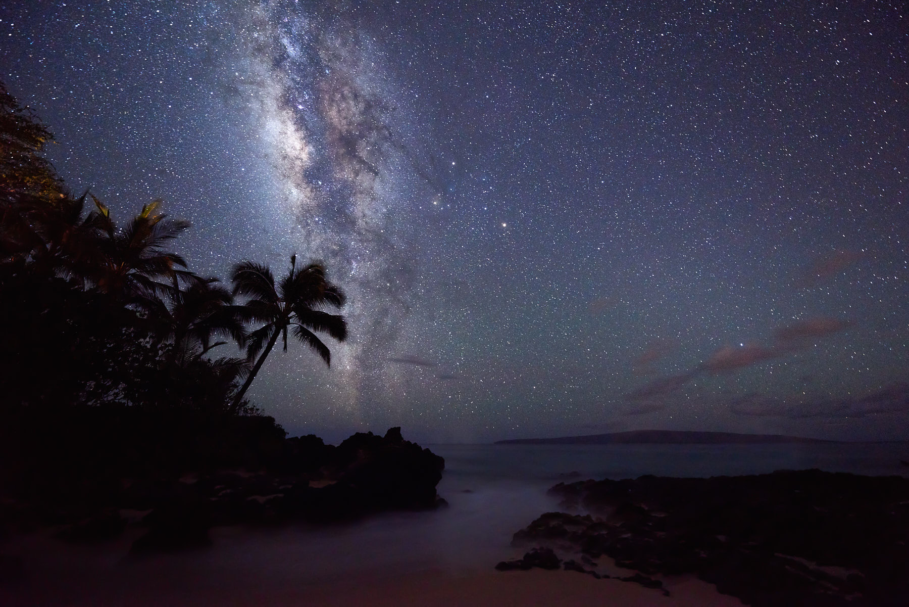 The core of the milky way galaxy rises over Secret Beach (also known as Makena Cove) at night on the island of Maui, Hawaii