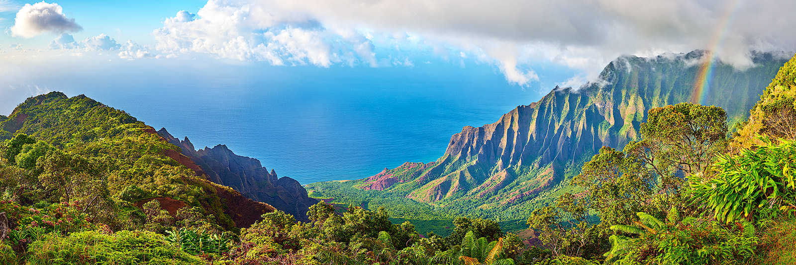a panorama of the Kalalau valley along the Na Pali coast on the Hawaiian island of Kauai featuring a rainbow and dramatic light.  Fine Art Hawaii Photography