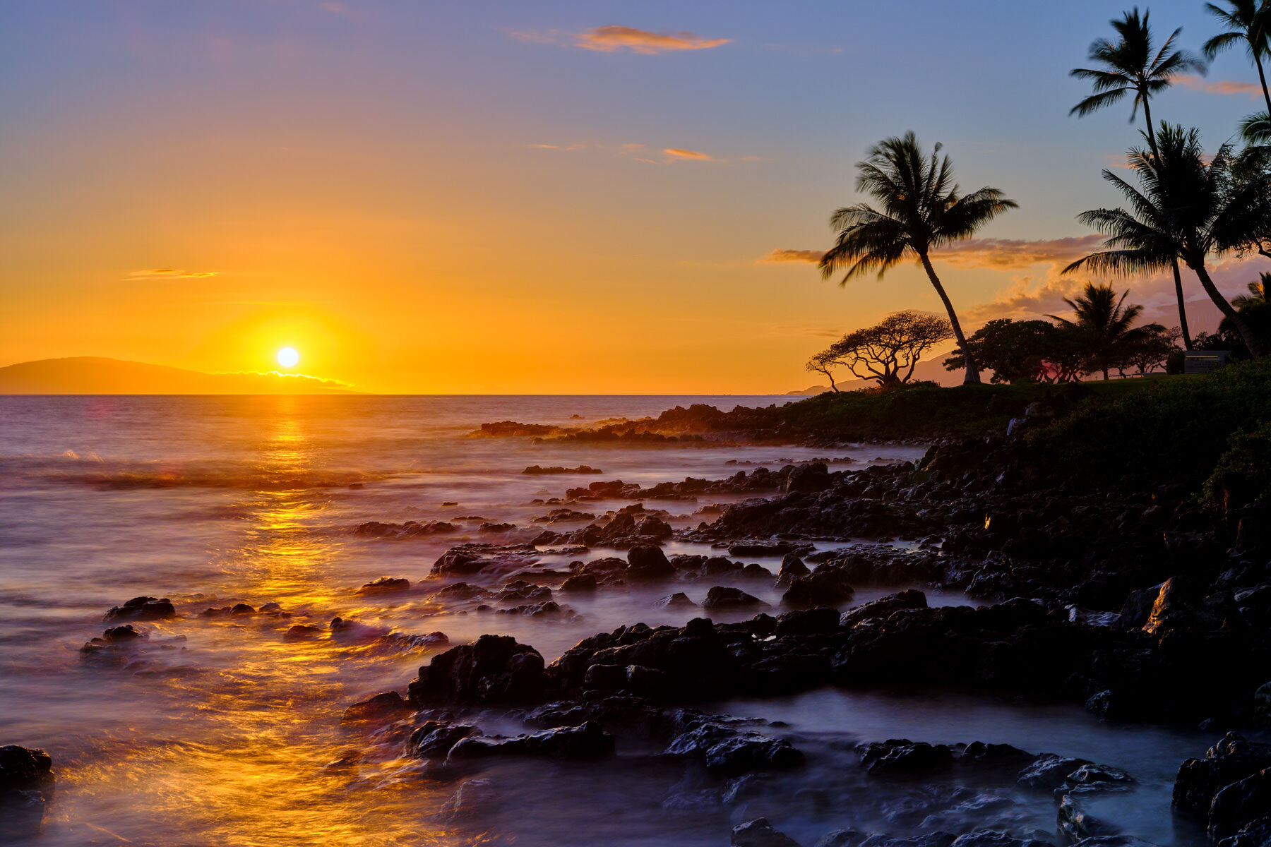 Last Glimpse the setting sun casts it's warm glow across the water at sunset in Wailea, Maui. Sunset photography by Hawaii artist Andrew Shoemaker