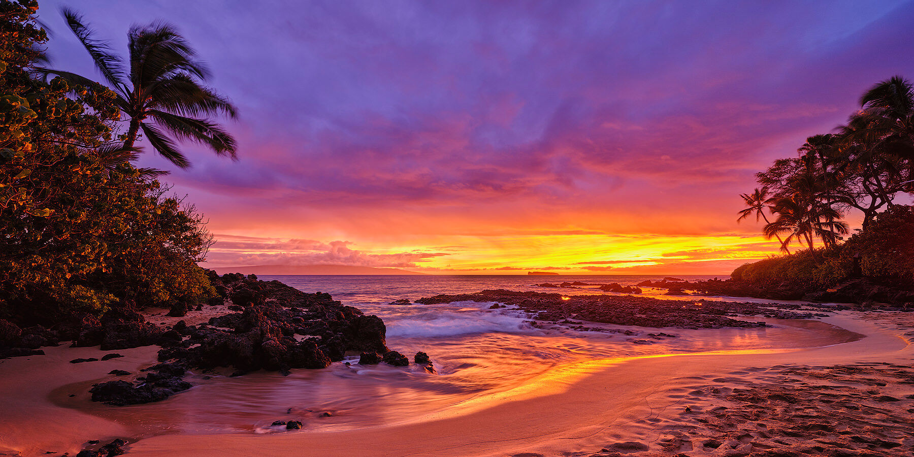 Nirvana panorama of a very dramatic and vibrant colored sunset erupts at Secret Beach in Makena on the island of Maui