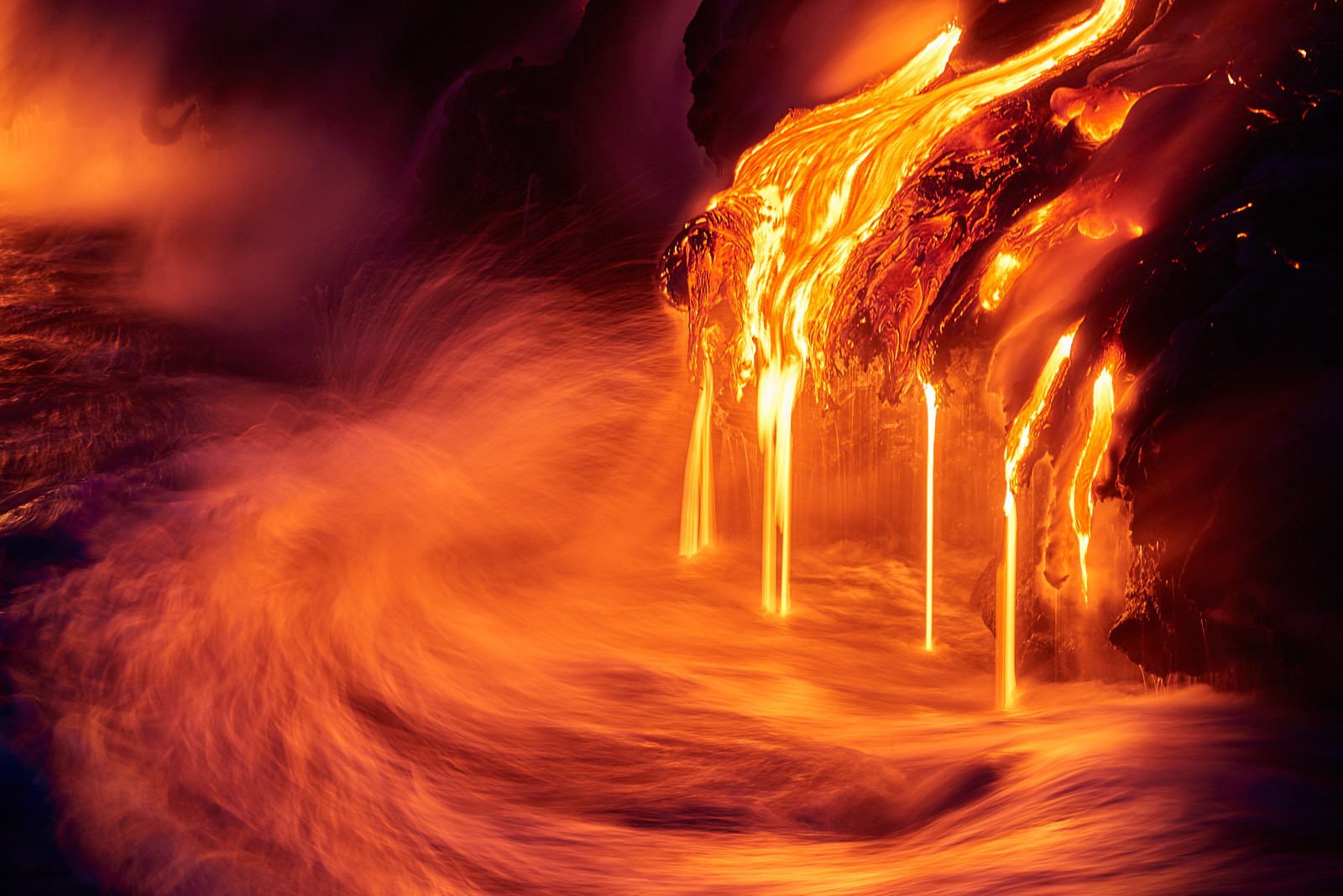 a long exposure photograph of lava entering the ocean at night along the coast of the Big Island of Hawaii in Volcanoes National Park