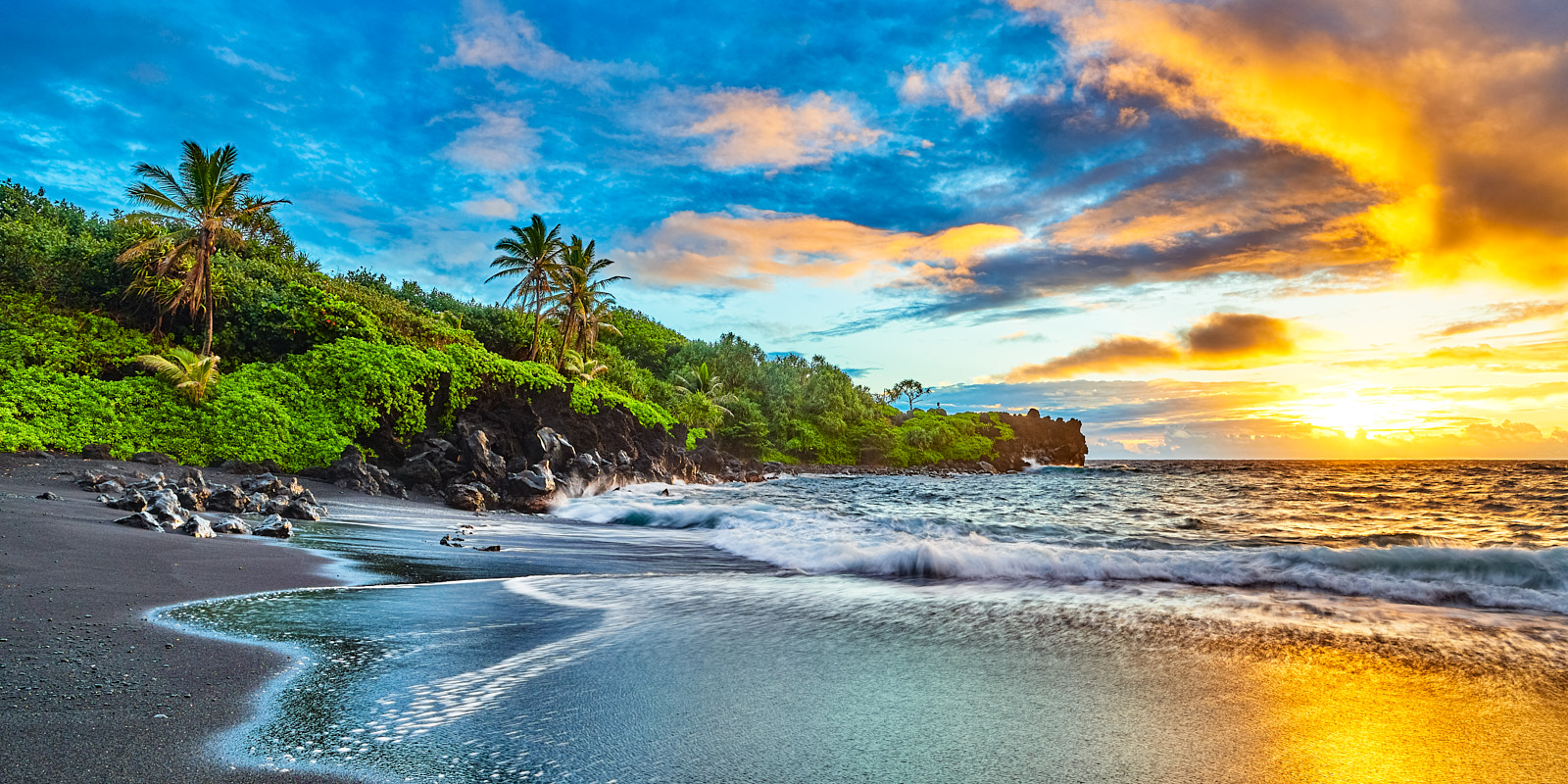 a vibrant sunrise at the famous black sand beach at Waianapanapa State Park near Hana on the island of Maui, Hawaii.