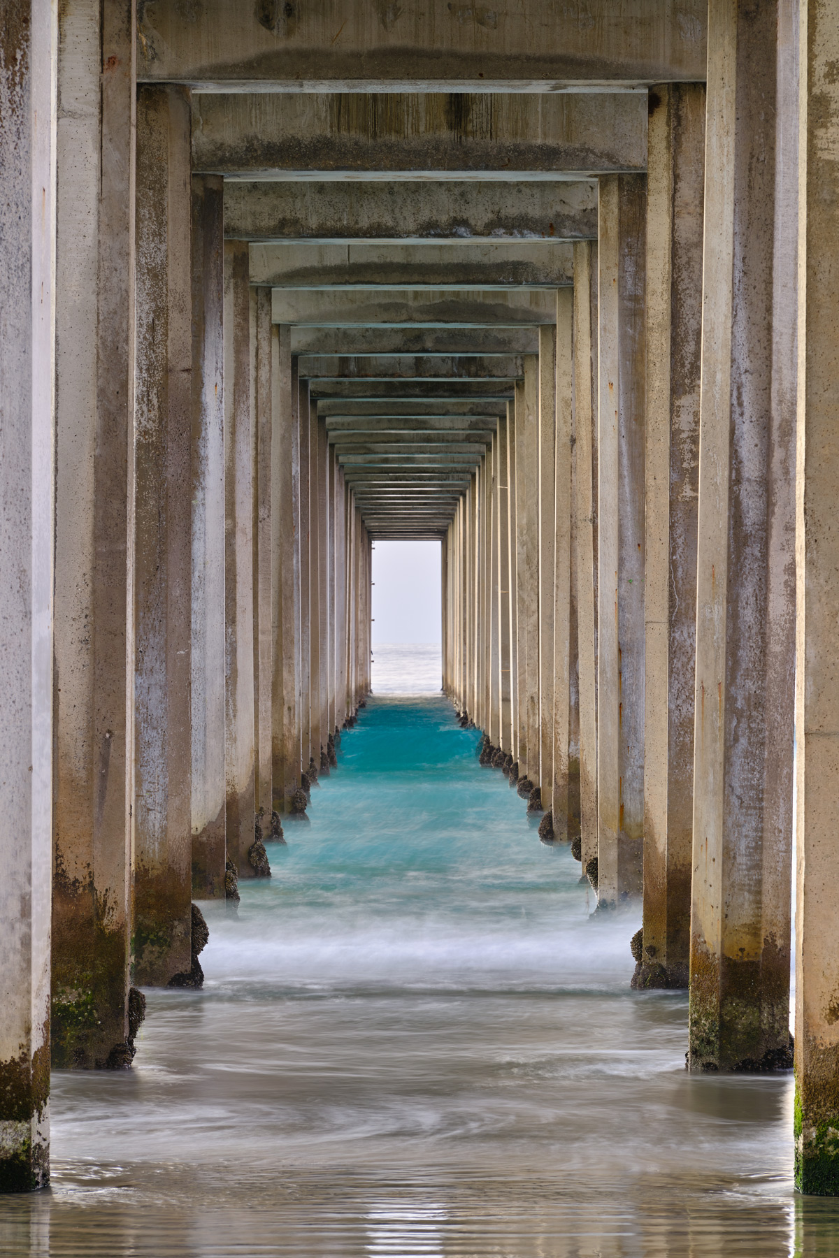 an abstract view looking down Scripps Pier in La Jolla, California near San Diego showcasing the perfect columns and blue water.  Photo by Andrew Shoemaker